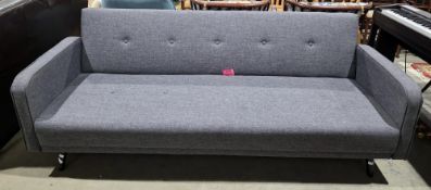 Modern click-clack style sofa bed upholstered in a buttoned grey twill fabric, on turned tapering