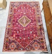 Large red ground rug with central geometric hexagonal medallion on floral field, geometric