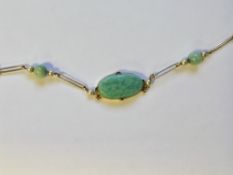 Yellow metal pendant necklace set with an oval cabochon jade panel and two jade beads,