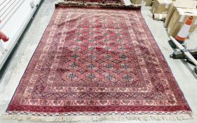 Large Eastern red ground rug with four rows of nine elephant foot guls on geometric field,