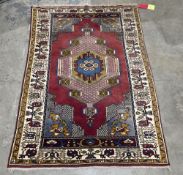 Turkish red ground rug with large central hooked geometric medallion, floral spandrels, flanked by