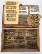 Box of brass metal shoulder titles including Bm825, Bm824 and others within a wooden box (please