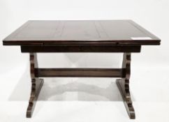 Mid 20th century dark oak draw-leaf dining table on trestle shaped supports, united by a cross