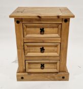 Modern pine bedside cabinet having three moulded drawers with metal drop ring handles, on a plinth