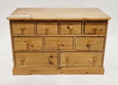Pine chest having a bank of nine short drawers with turned wooden handles, on a plinth base, 61cm