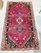 Large Eastern red ground rug with three central hexagonal medallions on floral field, multiple