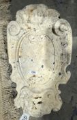 Carved stone, possibly granite, plaque with scrolling border, lion's mask below putto, vacant scroll