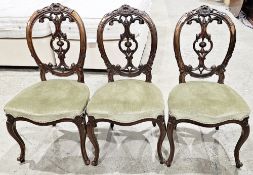 Set of three Victorian mahogany balloon back dining chairs with carved top rails and splats, green
