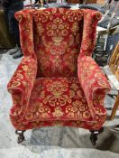 Wing back armchair in the George III manner, upholstered in a red floral patterned carpet-type
