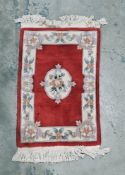Chinese red ground superwash rug with central floral medallion, single floral border, 99cm x 62cm