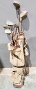 Early 20th century canvas and leather golf bag holding a collection of golf clubs, including a