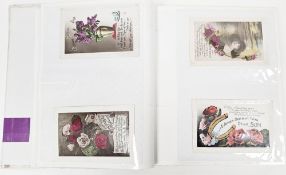 An album of early 20th century mainly coloured greetings postcards including birthday, Christmas,