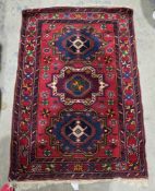 Eastern red ground rug with one row of three geometric medallions on floral and geometric shaped