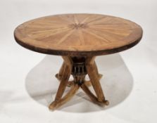Circular hardwood table, the top formed from an iron bound cartwheel, supported by a cartwheel