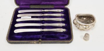 Oval silver salt on four ball feet, a silver thimble and five cake knives with silver handles,