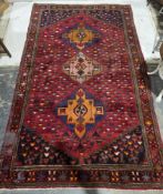 Eastern red ground carpet with three hooked lozenge medallions on geometric shape field, geometric