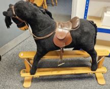 Mamas and Papas rocking horse with black body on a wooden base labelled 