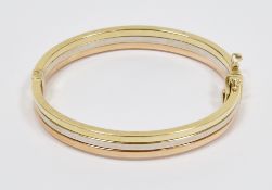 Three-colour gold hinged bangle of plain form with a band of rose, white and yellow gold, marked
