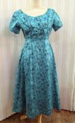 A 1950's cocktail dress ballerina length, with a boned inner bodice, turquoise brocade with black