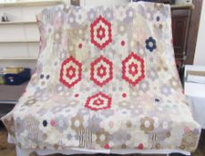 A large patchwork quilt, with five large red hexagonal blocks centre, there is some staining or