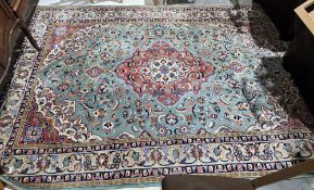 Large Persian-style green ground rug wituh central floral motifs on floral field and spandrels,