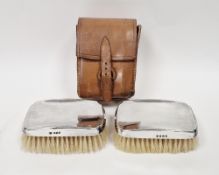 Pair of silver-backed brushes of shaped rectangular form, in leather case