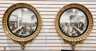 Pair of Regency-style giltwood convex wall mirrors with black eagle and giltwood cresting, the