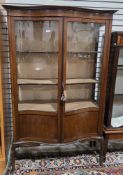Early 20th century mahogany display cabinet of serpentine form, the two partially glazed panel doors