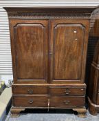 Early 19th century mahogany wardrobe, the moulded top with carved frieze, over two panel doors