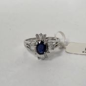 18k white gold, sapphire and diamond cluster ring, claw set with an oval mixed cut sapphire (approx.