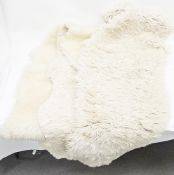 Three sheepskin floor rugs, one by Bowron, the largest 180cm long