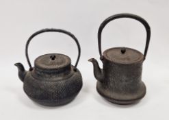 Two Japanese cast iron teapots and covers (Tetsubin), the first cast with dimples, with swing