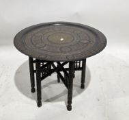 Brass-top Benares-style folding table, the circular brass top with engraved decoration, on a