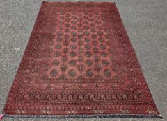 Large red ground wool pile rug with four alternating rows of ten elephant foot guls and three rows