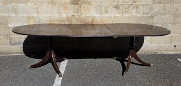 Mahogany twin-pedestal dining room table in the Regency manner, the top with rounded ends and one