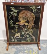 Early 20th century oak framed firescreen having a needlework panel decorated with exotic birds