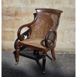 Regency mahogany and bergere library chair, the top rail with carved scroll ends, foliate scroll