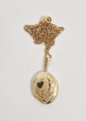 Yellow metal oval locket stamped M14K, the textured front with engraved leaf and heart decoration,
