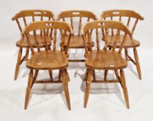 A set of five beechwood tub dining chairs with spindle backs on turned legs united by H