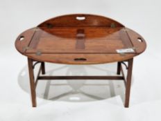Mahogany butler's tray-style coffee table of oval form, the lift-off tray top with four folding