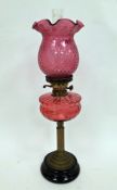 Late 19th / early 20th century oil lamp comprising a fluted cranberry shade and well, on a brass
