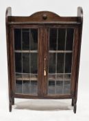 Early 20th century oak bow-fronted display cabinet, the two leaded glazed doors opening to two