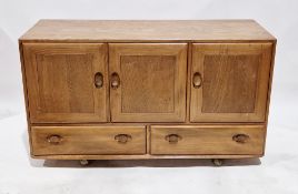 Ercol Windsor elm sideboard comprising three panel cupboard doors above two drawers, 76cm high x