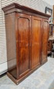 19th-century mahogany triple wardrobe, the moulded cornice over a pair of panel doors opening to a