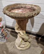 Two cast concrete bird baths, both of a circular form, one on a plinth cast as a tree trunk with