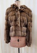 A mink short jacket, with full bell sleeves, cuffed, with a frilled collar, labelled Saga Furs,