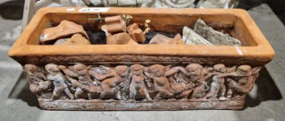 A terracotta rectangular garden planter decorated with moulded cherubs, with four lion's head