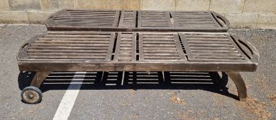A pair of two-wheeled teak slatted garden loungers, 198cm L x 63cm wide