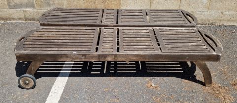 A pair of two-wheeled teak slatted garden loungers, 198cm L x 63cm wide