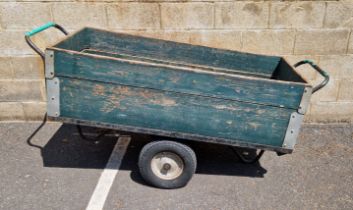 Early to mid-20th century green painted wooden tote cart having two central wheels and a tubular